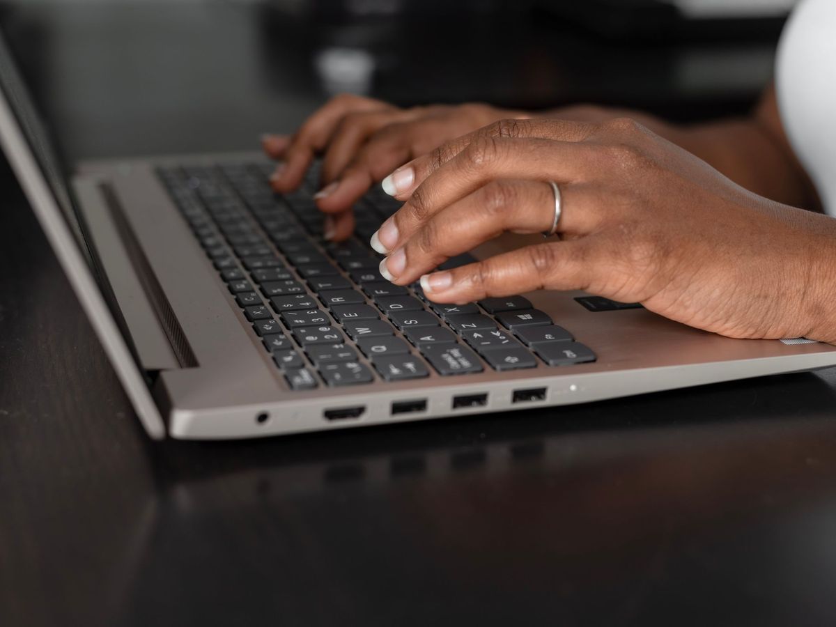 Close-up of hands typing on a laptop keyboard